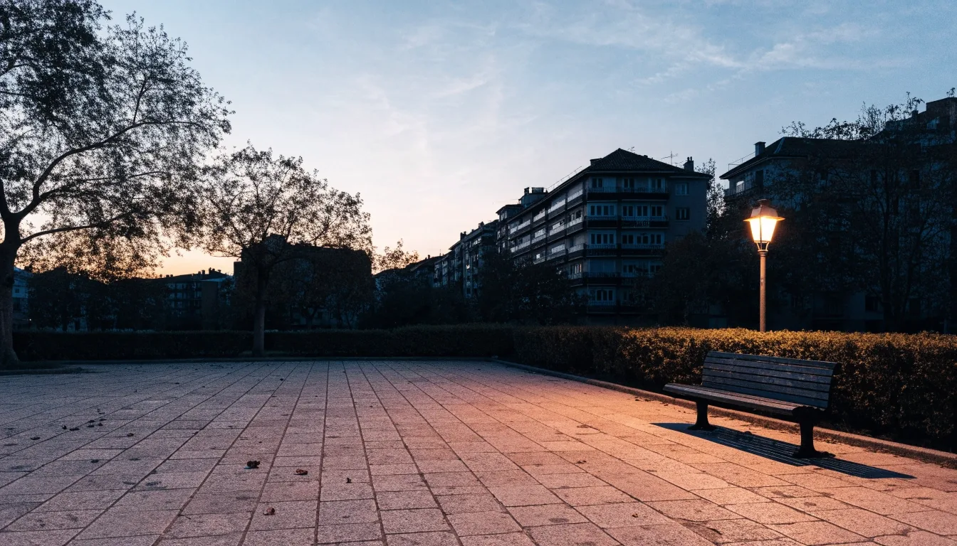 Plaza madrileña al atardecer de otoño, con un banco vacío y los balcones de las viviendas al fondo